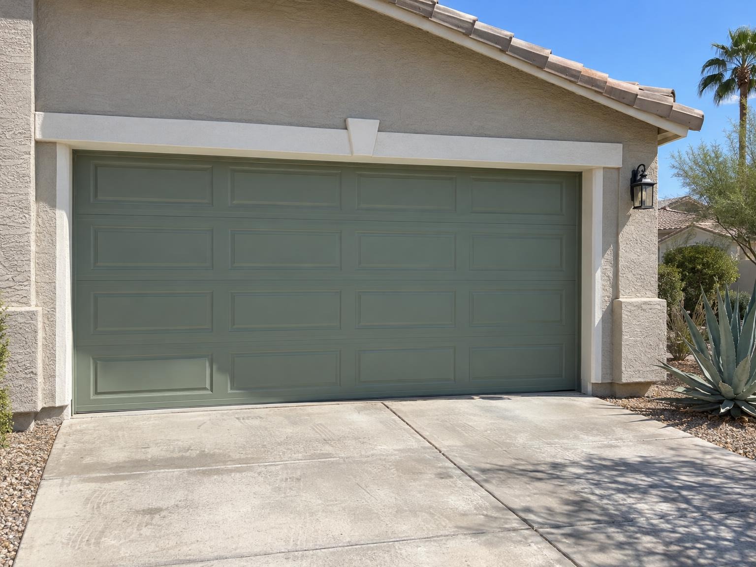 Sage green garage door on a greige stucco house